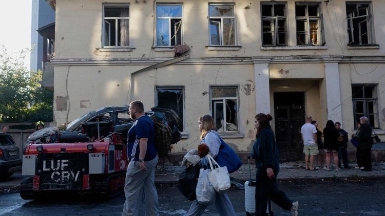 Pessoas caminham em frente a um pr&eacute;dio residencial danificado ap&oacute;s um ataque russo em Kiev, em 20 de agosto de 2026, em meio &agrave; invas&atilde;o da Ucr&acirc;nia pela R&uacute;ssia. O bombardeio russo matou seis pessoas e feriu dezenas na capital ucraniana e na regi&atilde;o circundante durante a noite, disseram as autoridades em 20 de agosto. (Foto de Tetiana DZHAFAROVA / AFP)