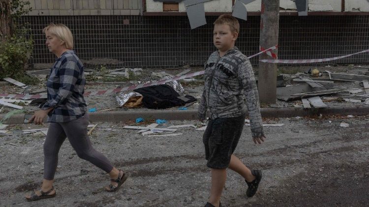 Pessoas caminham ao lado de corpos perto de um pr&eacute;dio residencial danificado em um ataque russo a Kiev, que tamb&eacute;m atingiu um hospital pr&oacute;ximo, em 20 de agosto de 2026, em meio &agrave; invas&atilde;o russa da Ucr&acirc;nia. Os bombardeios russos mataram pelo menos 12 pessoas e feriram dezenas na capital ucraniana e na regi&atilde;o circundante durante a noite, disseram as autoridades em 20 de agosto. (Foto de Roman PILIPEY / AFP)