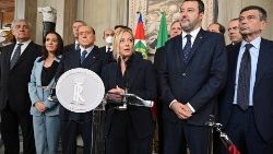 Giorgia Meloni (C) speaks at a press conference, flanked by Matteo Salvini (R) and Silvio Berlusconi (L)