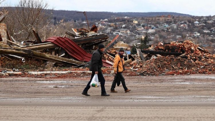 Um casal caminha perto dos escombros de edifícios destruídos em Kupiansk, região de Kharkiv, Ucrânia, 8 de fevereiro de 2024, em meio à invasão russa. De acordo com autoridades ucranianas, as forças russas têm intensificado a sua ofensiva na área da frente de Kupiansk há mais de seis meses, enquanto tentam recuperar o controlo da cidade desde 2022, quando as forças ucranianas recapturaram o controlo da área na contra-ofensiva de Kharkiv. EPA/ANTÔNIO COTRIM