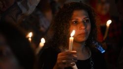 A woman holds a candle at a prayer vigil for peace