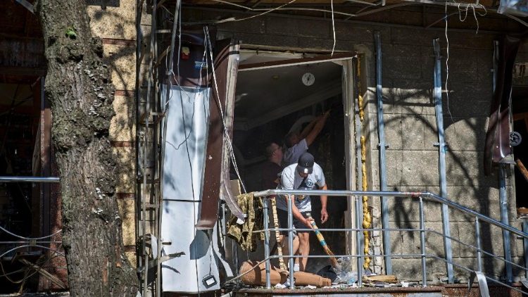 Pessoas limpam destroços no local de um ataque com bomba plana em um prédio residencial em Kharkiv, nordeste da Ucrânia, 22 de junho de 2024. EPA/SERGEY KOZLOV