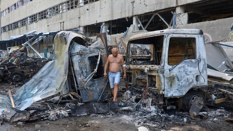Uma pessoa ferida inspeciona carros danificados no local de uma bomba plana atingida em um terminal postal em Kharkiv, nordeste da Ucrânia, 30 de junho de 2024. EPA/SERGEY KOZLOV