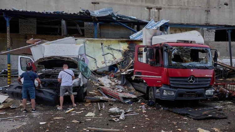 Motoristas inspecionam carros danificados no local de uma bomba plana atingida em um terminal postal em Kharkiv, nordeste da Ucrânia, 30 de junho de 2024. EPA/SERGEY KOZLOV