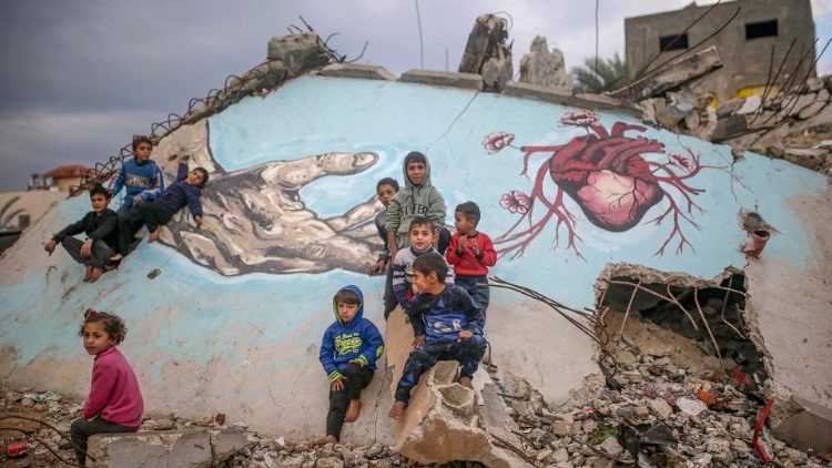 Niños palestinos desplazados juegan junto a un mural pintado sobre los escombros de una casa dañada en la ciudad de Deir Al Balah, en el centro de la Franja de Gaza, 2 de diciembre de 2024. 