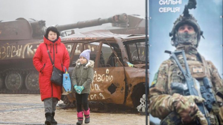 Uma mulher e uma criança passam por máquinas militares russas destruídas e veículos civis ucranianos danificados expostos perto da Catedral de St. Mykhailivsky no centro de Kiev, Ucrânia, 09 de dezembro de 2024, em meio à invasão russa em andamento. EPA/SERGEY DOLZHENKO 71058