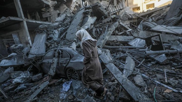 A woman walks among the rubble following an Israeli airstrike in Al Nuseirat refugee camp on December 13