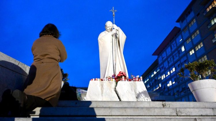 Frau im Gebet vor der Statue Johannes Paul II. im Vorhof der Gemelli-Klinik