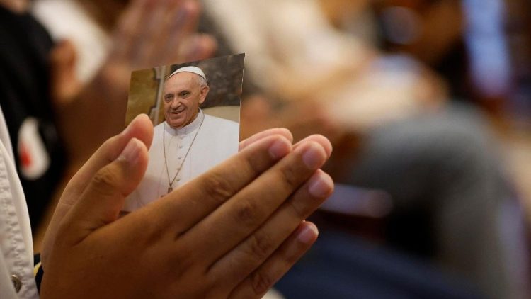 L'effigie du Pape François, dans les mains d'une personne en prière. 