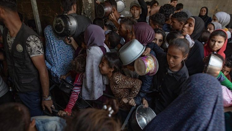 Centenas de deslocados palestinos tentam receber alimentos na "Sokar Charity Kitchen" na Cidade de Gaza
