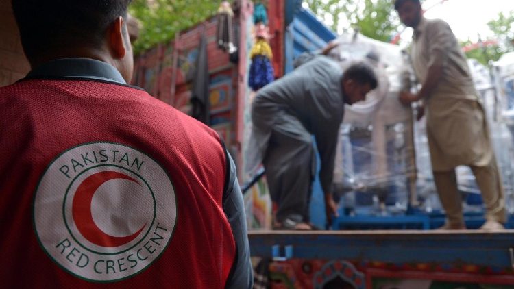 Volunteers from the International Red Crescent Societies (IFRC) loads relief goods for people who were affected by flooding from monsoon rains in the Khyber Pakhtunkhwa province