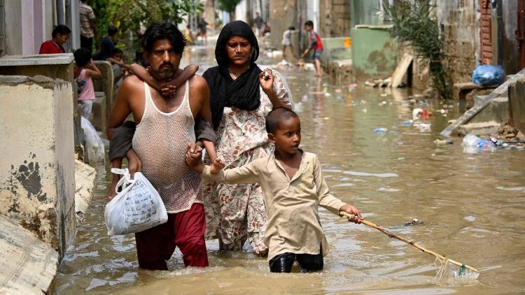 Una famiglia nelle strade allagate di Karachi