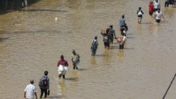 Pessoas atravessam uma rua alagada após fortes chuvas em um subúrbio de Colombo, Sri Lanka, em 30 de novembro de 2025. Muitas partes da ilha foram inundadas devido às fortes chuvas. EPA/CHAMILA KARUNARATHNE