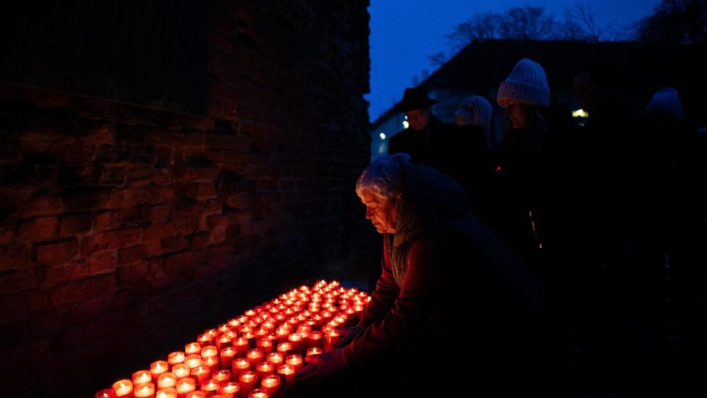 Una mujer lleva velas mientras rinde homenaje en una ceremonia conmemorativa del Día Internacional de Conmemoración del Holocausto. Cementerio judío cercano al antiguo campo de concentración nazi de Terezin, República Checa.  EPA/MARTIN DIVISEK  