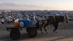 Sfollati palestinesi trasportano taniche d'acqua a Khan Younis