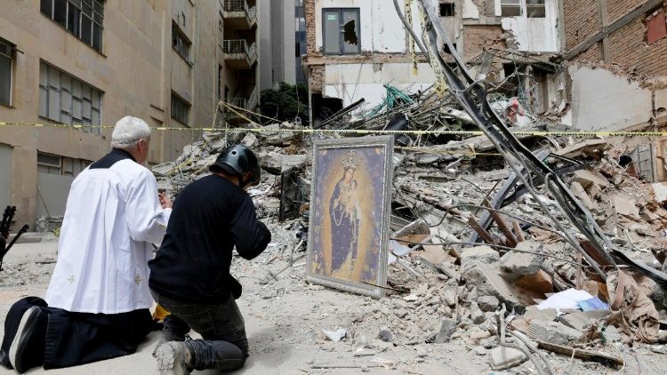 O padre Nelson Giraldo Mejia reza pelas vítimas do terremoto em frente aos escombros do edifício Santiago Londoño. EPA/CARLOS ORTEGA