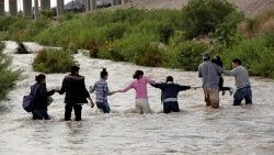 Migrants from Central American form a human chain to cross the Rio Bravo in order to enter the United States