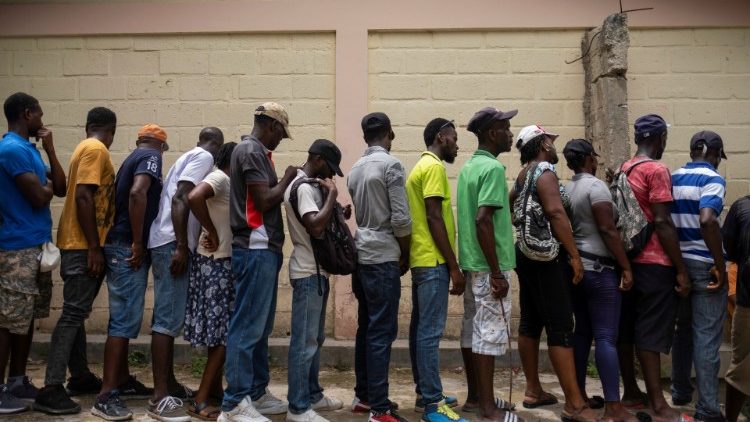 People wait for food at a school in Port Salut