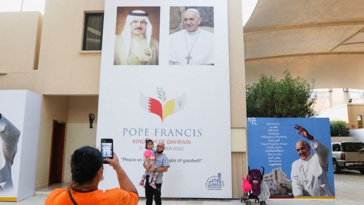 A visitor take photo in front of welcome banner for Pope Francis at Sacred Heart Catholic Church in Manama