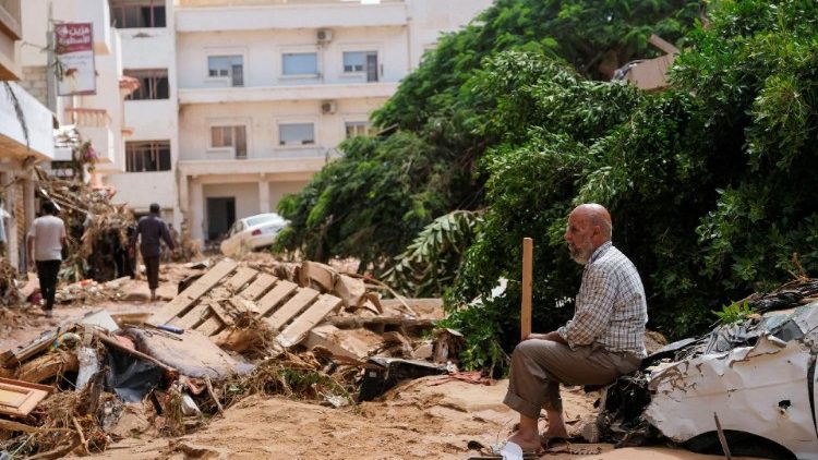 Ein Mann sitzt in Darna auf den Überresten eines Autos