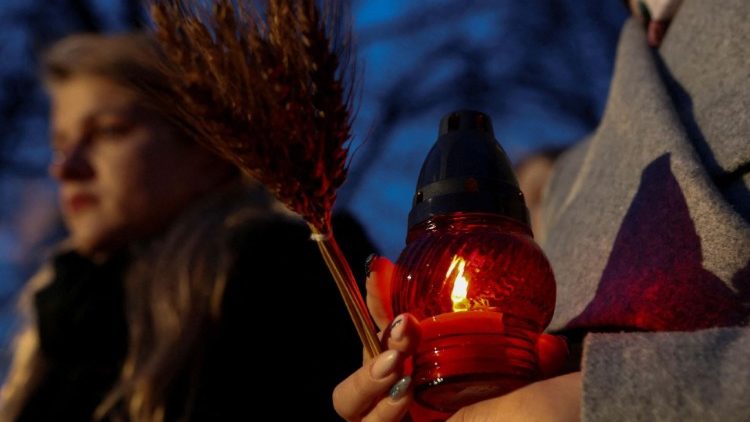 Uma mulher segura uma vela e espigas de trigo enquanto visita um monumento às vítimas do Holodomor durante uma cerimônia que comemora a fome de 1932-33, em que milhões morreram de fome, em Kiev, Ucrânia, em 25 de novembro de 2023. A cerimônia acontece durante a Rússia. ataque à Ucrânia. REUTERS/Sofia Gatilova
