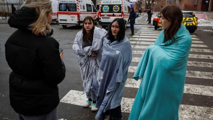 Moradores locais ficam perto de seu prédio danificado durante um ataque de míssil russo, em meio ao ataque da Rússia à Ucrânia, em Kiev, Ucrânia, 23 de janeiro de 2024. REUTERS/Gleb Garanich