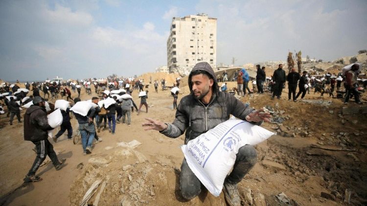Palestinians carry bags of flour they grabbed from an aid truck near an Israeli checkpoint in Gaza City