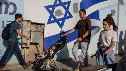 Un homme pousse une poussette devant un drapeau israélien à Tel-Aviv. 