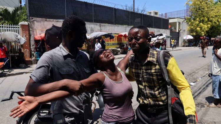 Haitiana é ajudada por outras pessoas ao ver o corpo de seu irmão, morto a tiros por desconhecidos, em Porto Príncipe, Haiti.