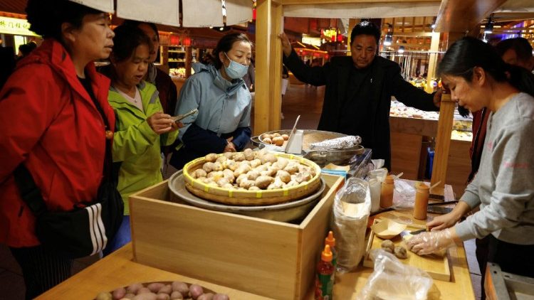 Un grupo de personas compra comida en un puesto de un mercado nocturno durante una visita organizada para la prensa en Dunhuang, China. (REUTERS)