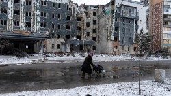 FILE PHOTO: A woman walks past a building damaged by a Russian military strike in the town of Pokrovsk