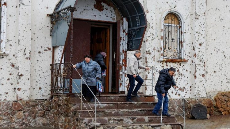 Fiéis saem do Mosteiro de St. Iveron, fortemente danificado pela artilharia durante as batalhas pelo aeroporto local, após o culto de Natal Ortodoxo durante o conflito Rússia-Ucrânia em Donetsk, região ucraniana controlada pela Rússia, em 7 de janeiro de 2025. REUTERS/Alexander Ermochenko