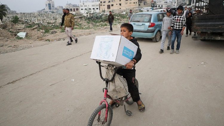 Palestinian boy carries an aid box provided by UNRWA, amid a ceasefire between Hamas and Israel, in Gaza City
