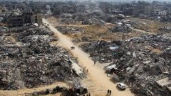 Palestinos passam pelos escombros de edifícios destruídos durante a ofensiva israelense em Rafah (Reuters)