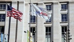 Una bandera estadounidense y otra de USAID ondean frente al edificio de USAID en Washington