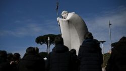 Fedeli in preghiera per la guarigione del Papa sotto la statua di San Giovanni Paolo II al Gemelli
