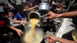 उत्तरी गाजा पट्टी के जबालिया में एक चैरिटी रसोई द्वारा पकाए गए भोजन का इंतजार करते फिलिस्तीनी