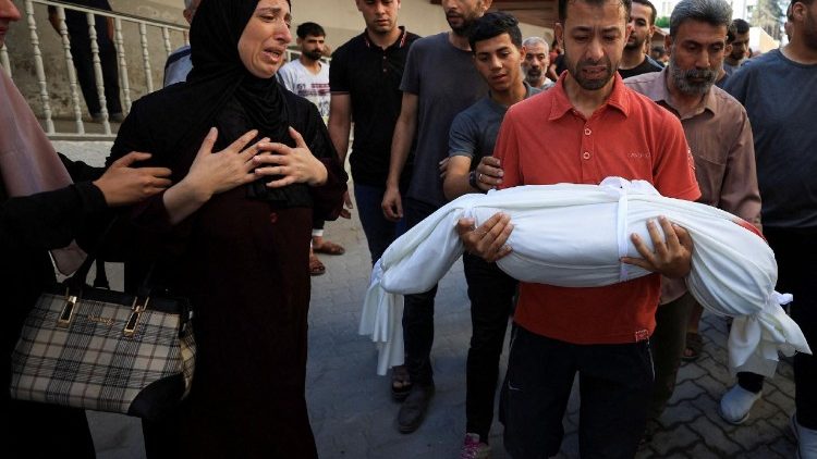 Mourners react near the body of a Palestinian child killed in an Israeli strike, in Gaza City