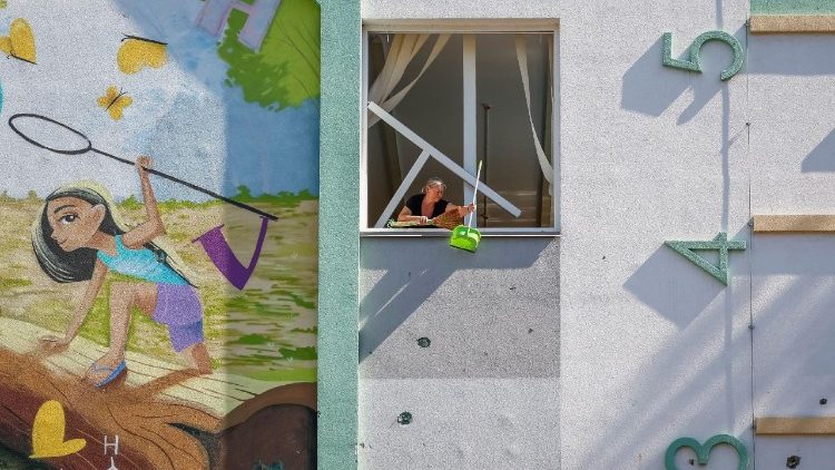 A woman cleans up a broken window in a damaged school, which was hit during Russian drone and missile strikes