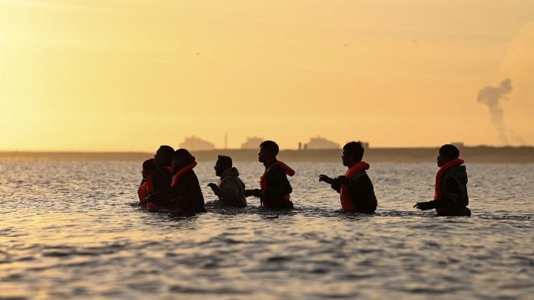 Мігранты спрабуюць дабрацца да надзіманай лодкі ў спробе пакінуць узбярэжжа паўночнай Францыі і перасекчы Ла-Манш, каб дасягнуць Вялікабрытаніі