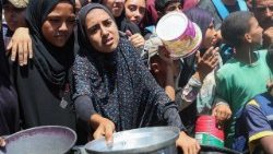 Palestinos se reúnen para recibir comida de una cocina benéfica, en medio de una crisis de hambre, en Nuseirat.