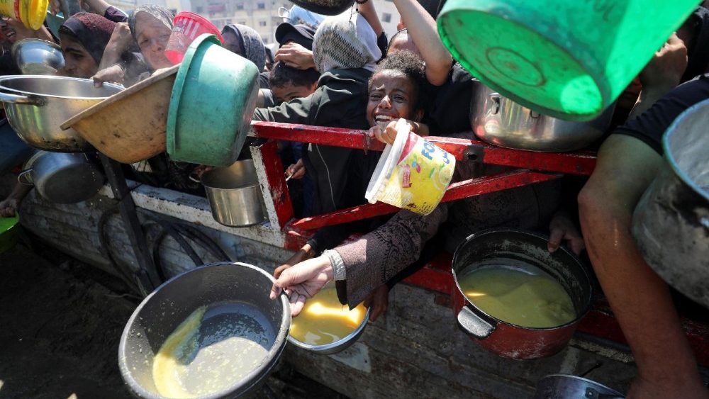Palestinians wait to receive food from a charity kitchen, in Gaza City