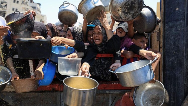 Palestinians wait to receive food from a charity kitchen, in Gaza City