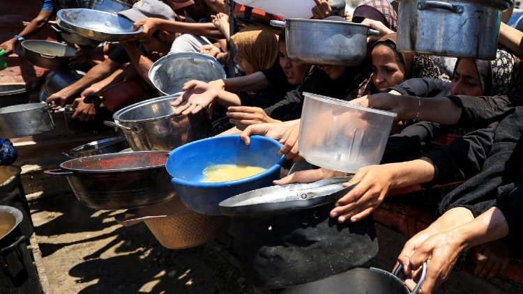Palestinians wait to receive food from a charity kitchen, in Gaza City