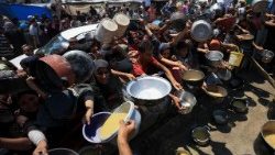 Palestinians gather to receive food from a charity kitchen, in Gaza City