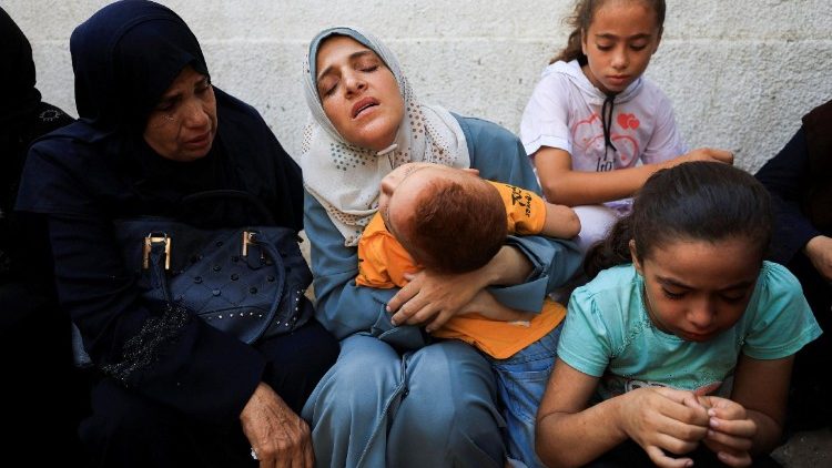 फिलीस्तीनी बच्चे और  वयस्क इस्राएल के हमले के बाद अंतिम संस्कार में भाग लेते हुए