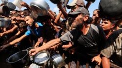 Palestinians wait to receive food from charity kitchen in Khan Younis