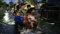 Pessoas andam em uma balsa improvisada para atravessar uma rua inundada após as chuvas, intensificadas pela forte tempestade tropical Bualoi, em Dela Paz, Binan, província de Laguna, Filipinas, em 26 de setembro de 2025. REUTERS/Noel Celis