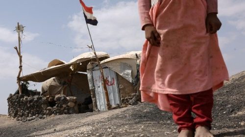 A displaced Yemeni girl stands outside her shelter inside a displaced persons camp in Marib, Yemen