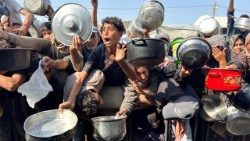 खान यूनिस में इजरायल और हमास के बीच युद्ध विराम के बीच फिलिस्तीनी एक चैरिटी रसोई से भोजन लेने के लिए इकट्ठा हुए